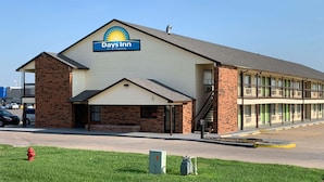 Un Days Inn by Wyndham con fachada de ladrillo, entrada cubierta y estacionamiento.