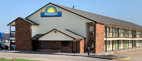 A Days Inn by Wyndham with a brick facade, a covered entrance, and a parking lot.
