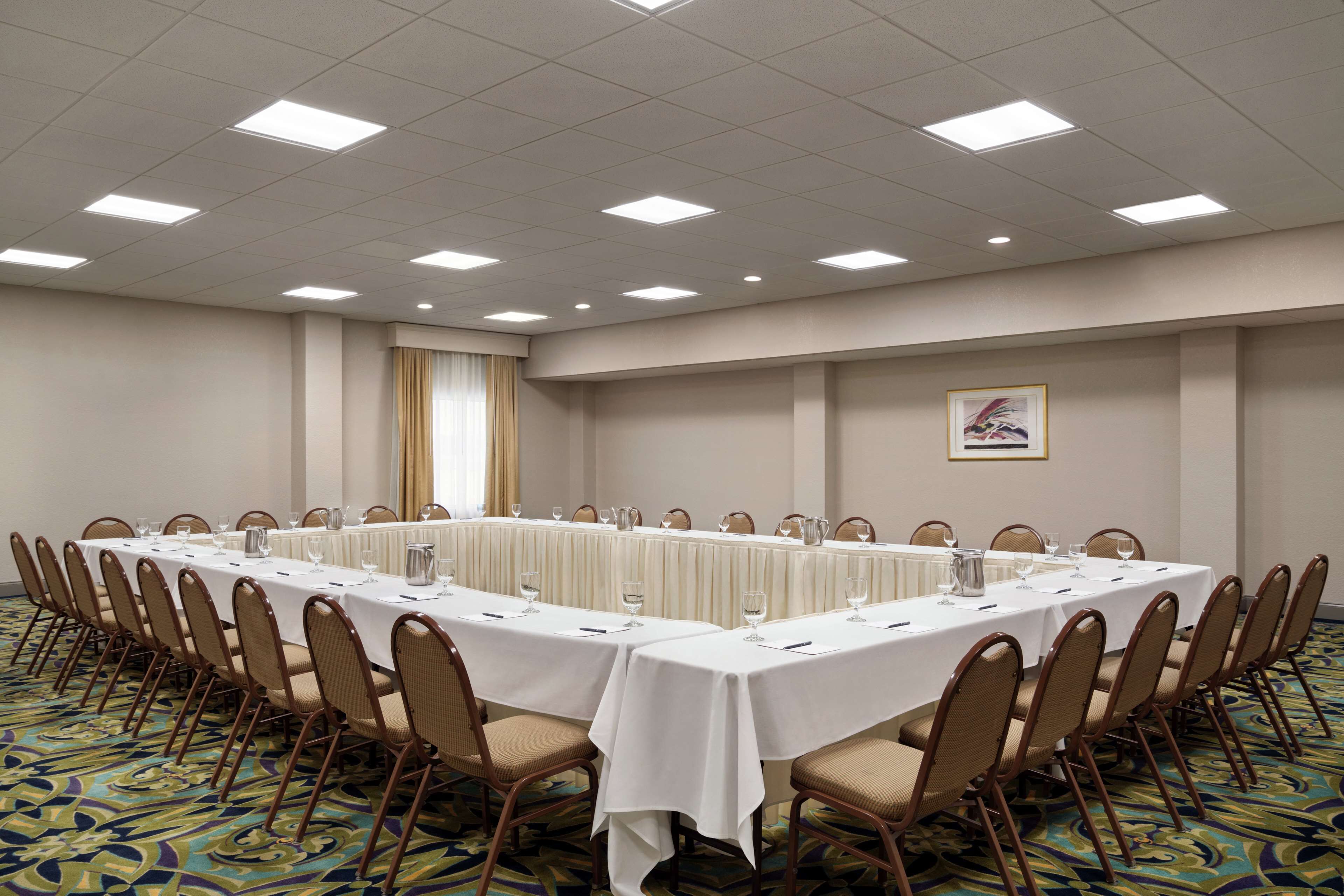 A conference room with a long table, chairs, and a framed picture on the wall.