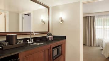 Un baño de hotel con lavamanos, espejo y cafetera.