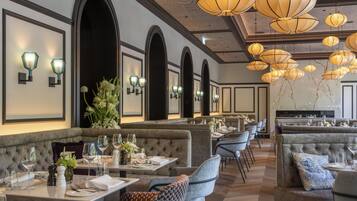 A restaurant with high-backed booths, a long counter, and hanging pendant lights.