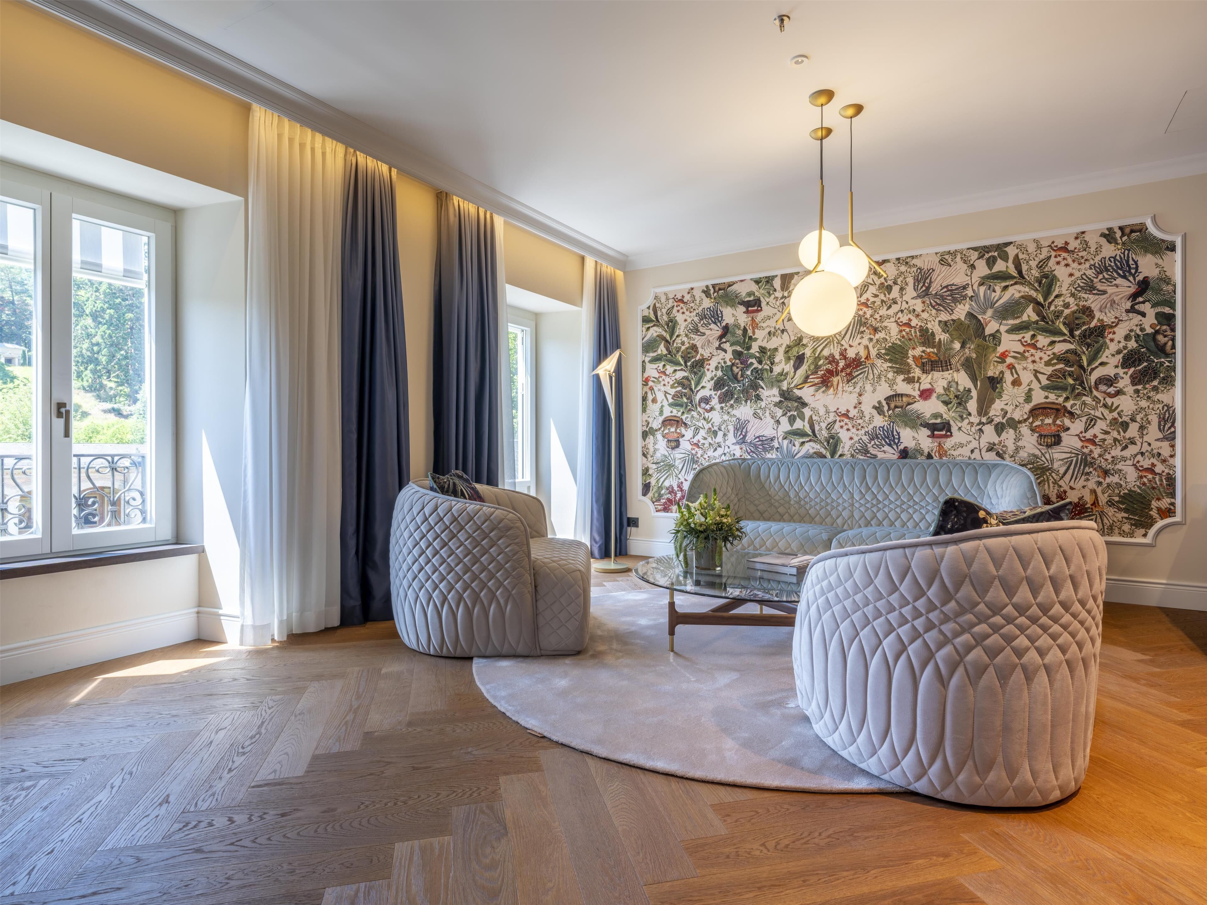 A modern living room with a sofa, ottoman, and a patterned wall.