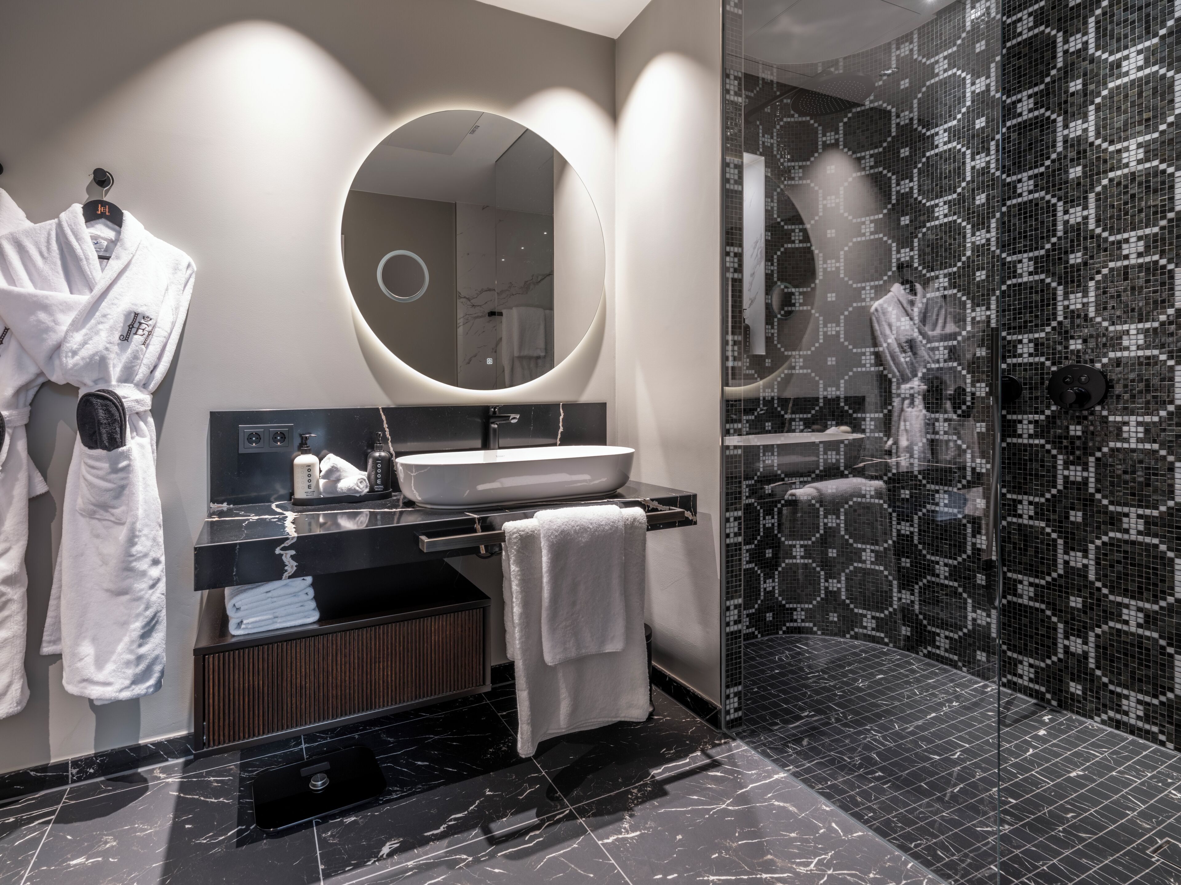 A modern bathroom with a large mirror, a sink, and a shower area.