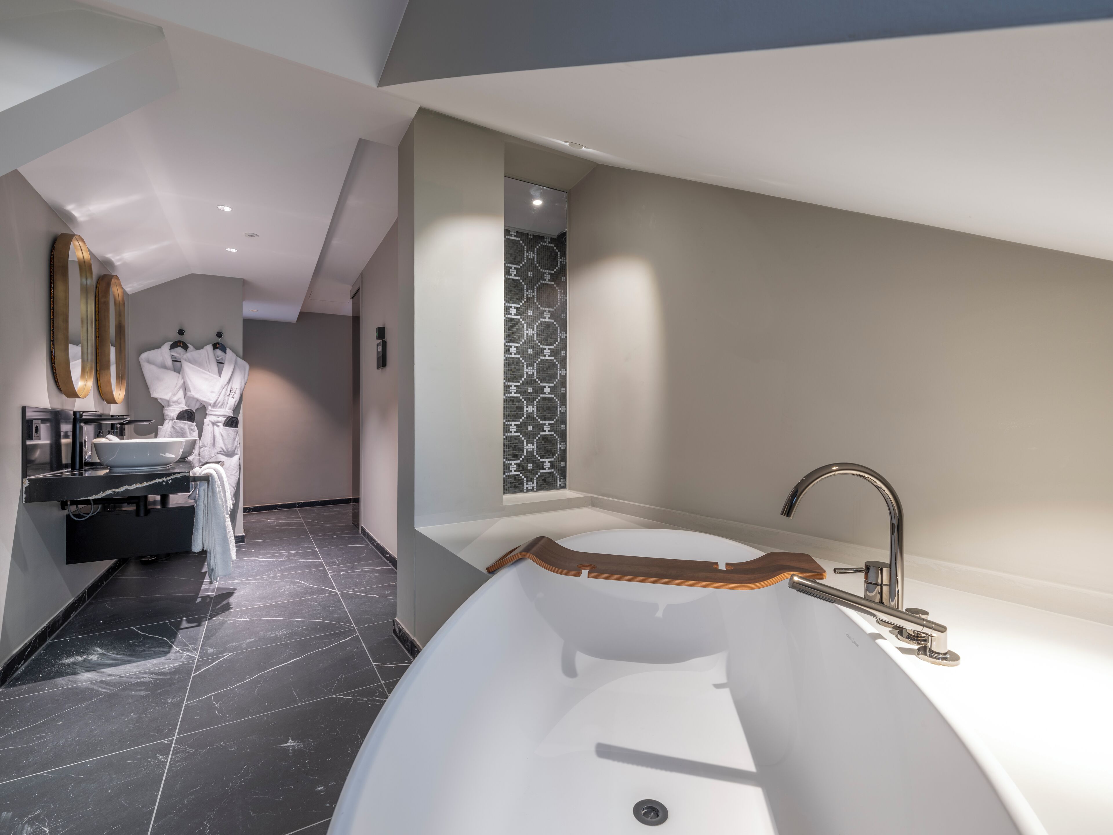 A modern bathroom with a large freestanding bathtub, a vanity with a bowl sink, and a mirror with a gold frame.