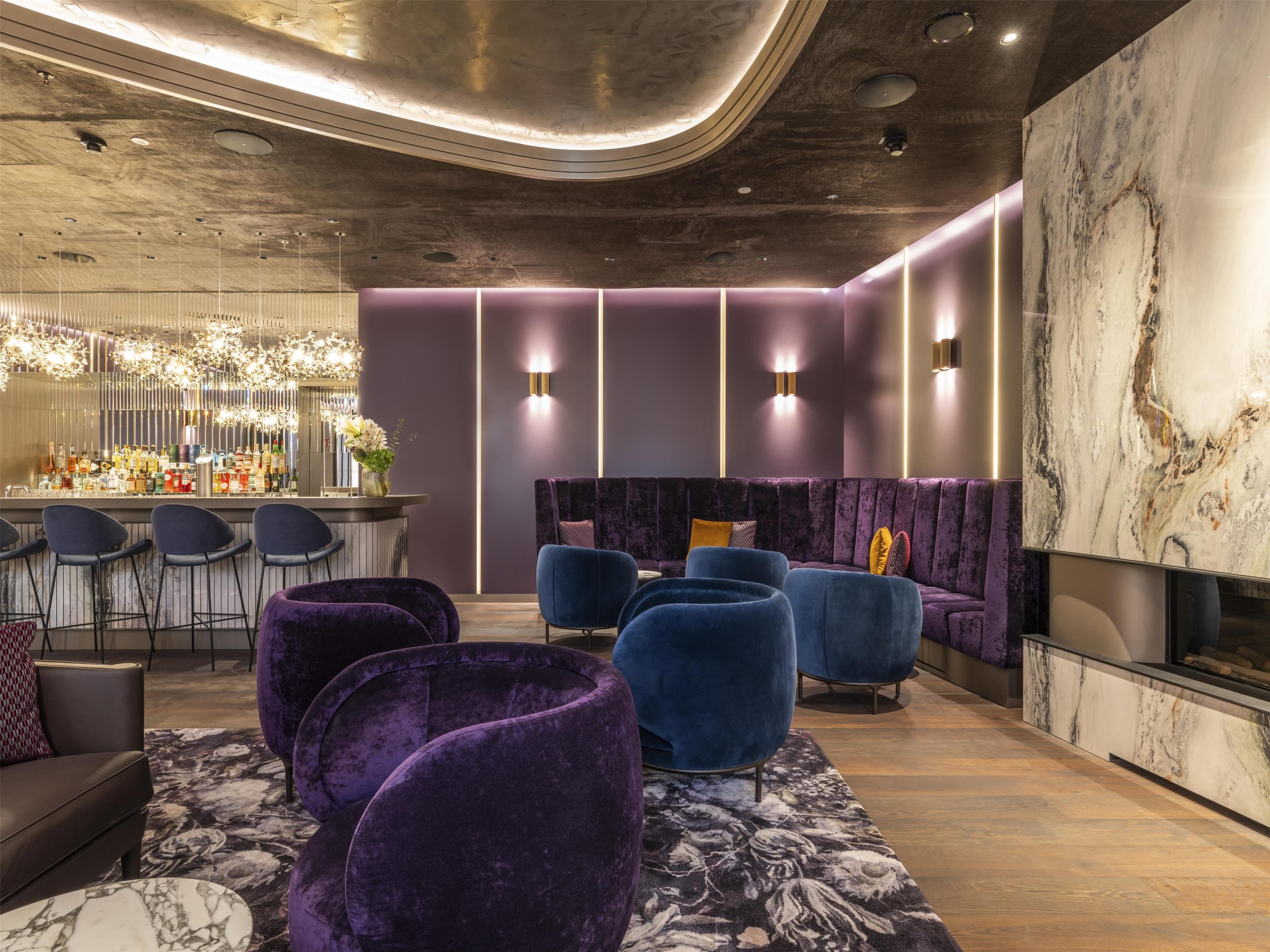 Un espace de détente moderne doté d’un bar, de sièges et d’une cheminée.