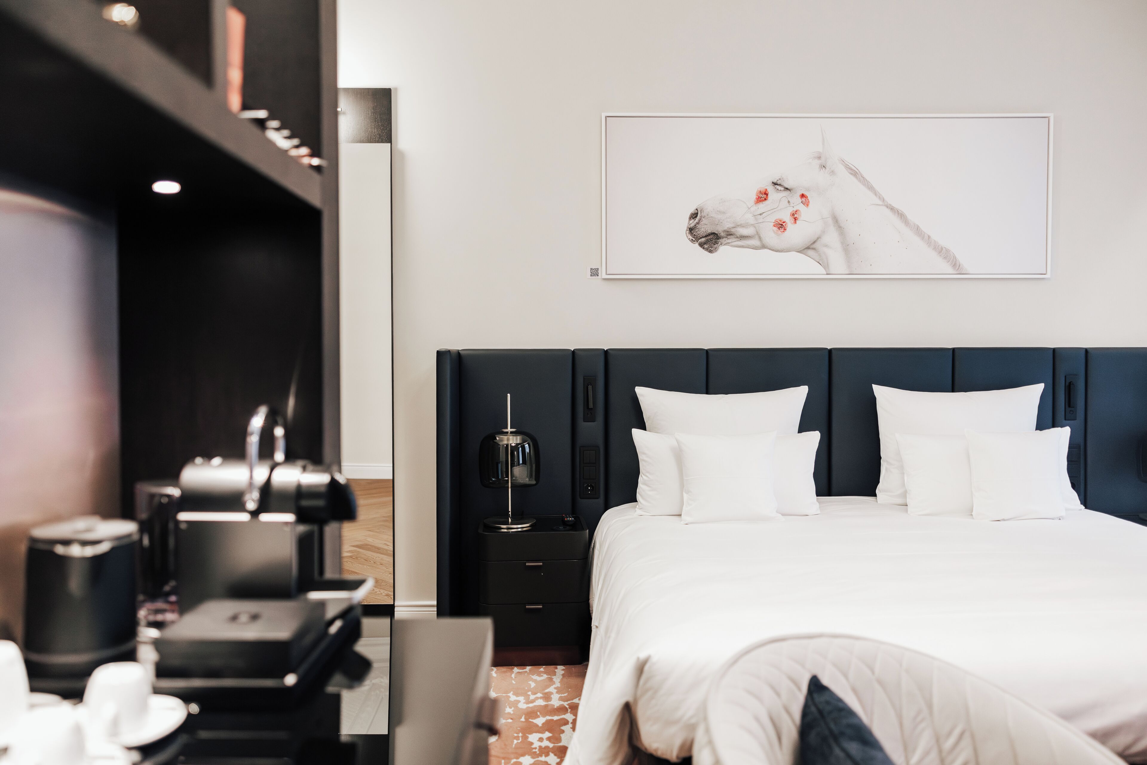 Una camera d'albergo moderna con un letto grande, una scrivania con una lampada e un quadro appeso al muro.