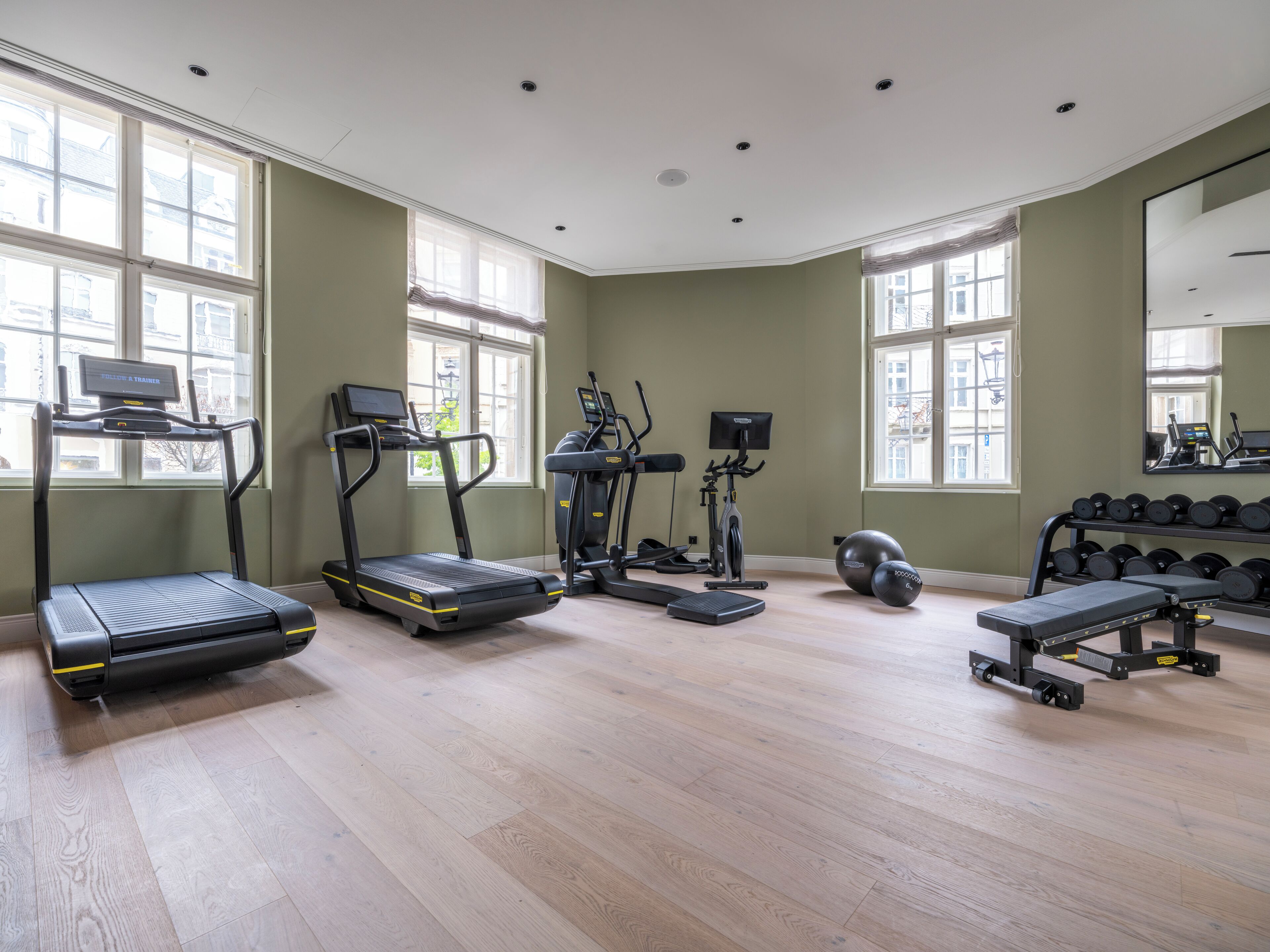 A spacious gym with treadmills, elliptical machines, and a bench press area.
