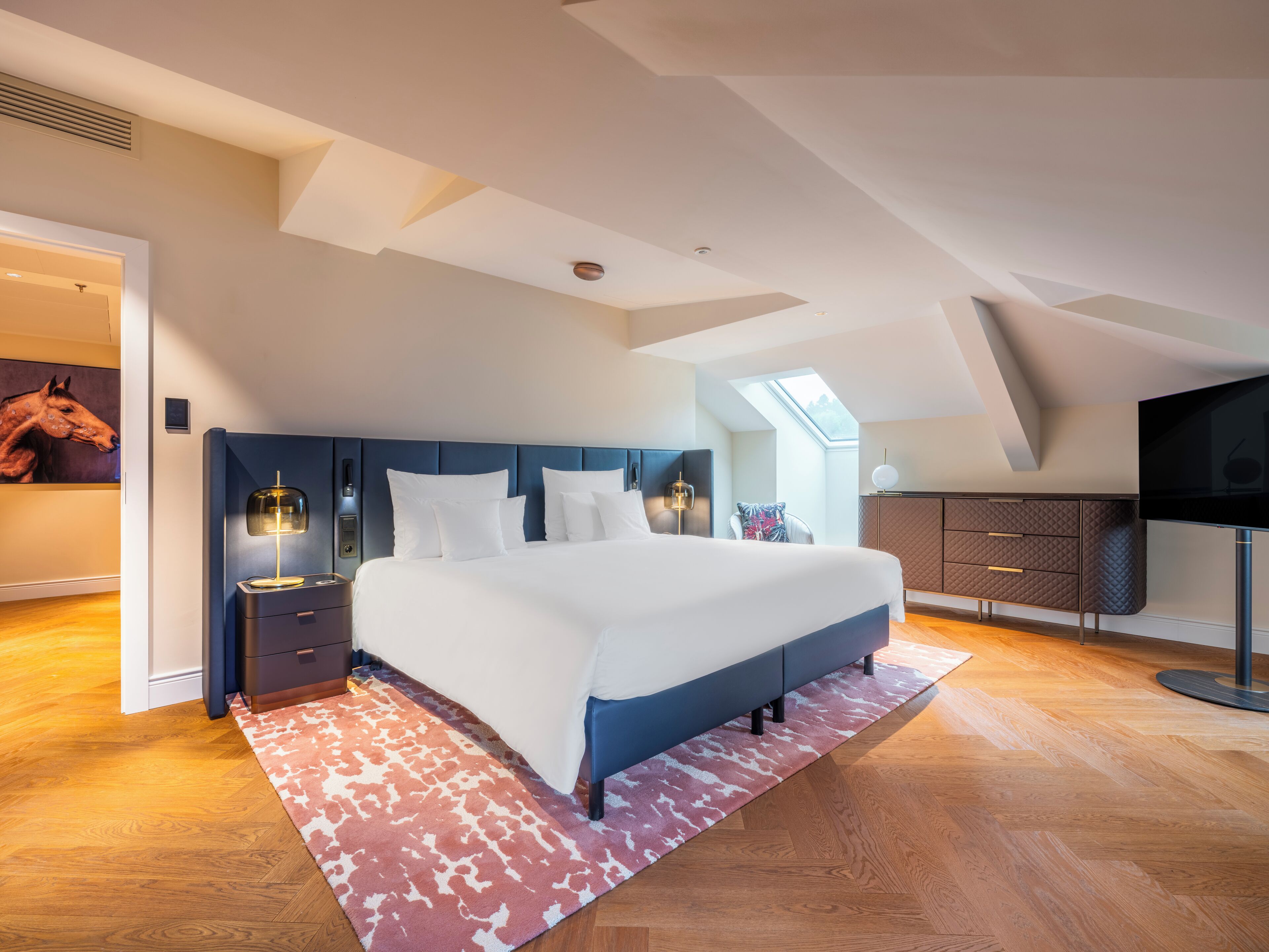 Un dormitorio moderno con una cama grande, televisión y tragaluz.