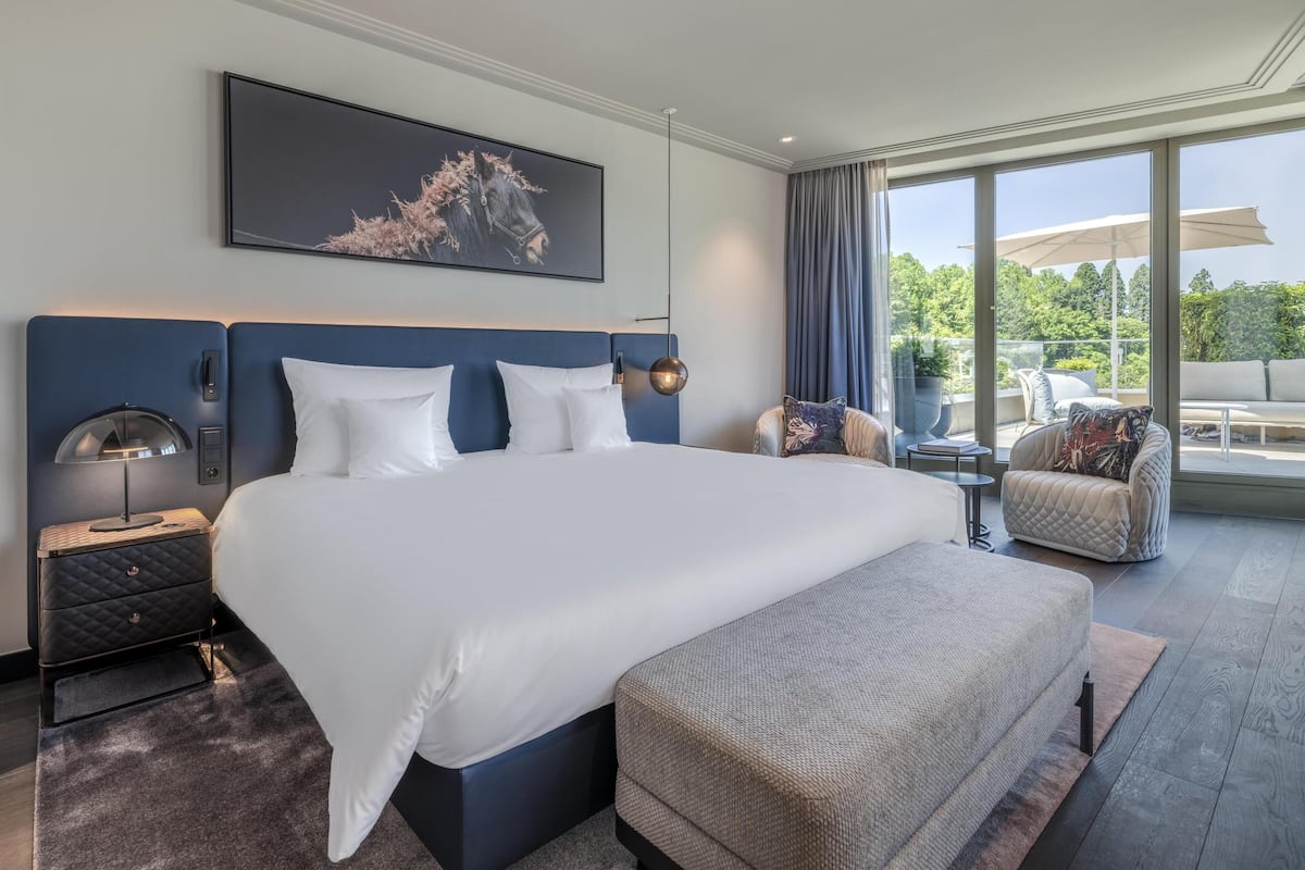 Une chambre d’hôtel moderne avec un grand lit, une table de chevet, un bureau et une vue sur l’extérieur.