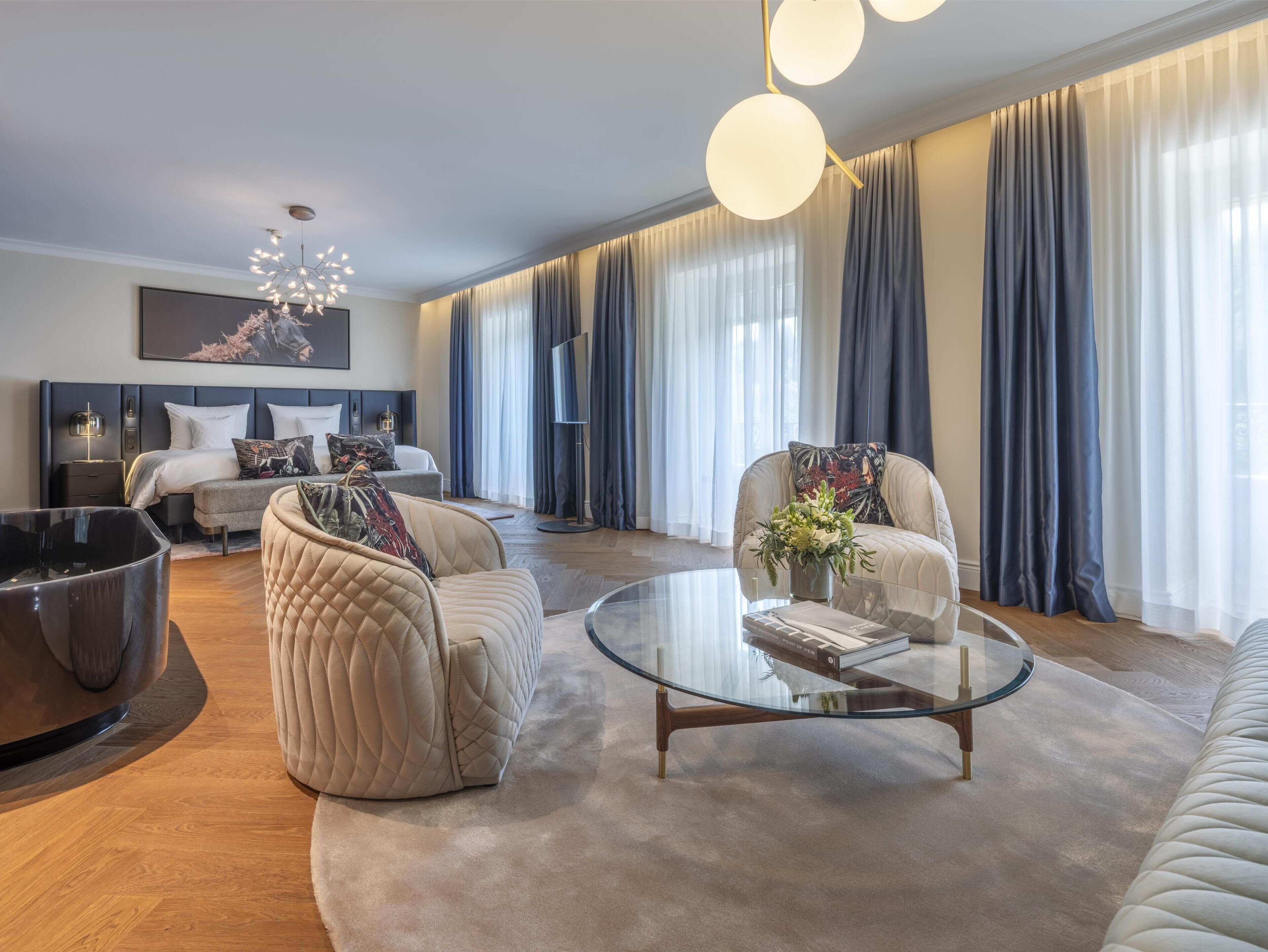 Una sala moderna con sofá, sillones, una mesa de centro y una cama con cabecera.