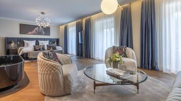 Una sala moderna con sofá, sillones, una mesa de centro y una cama con cabecera.