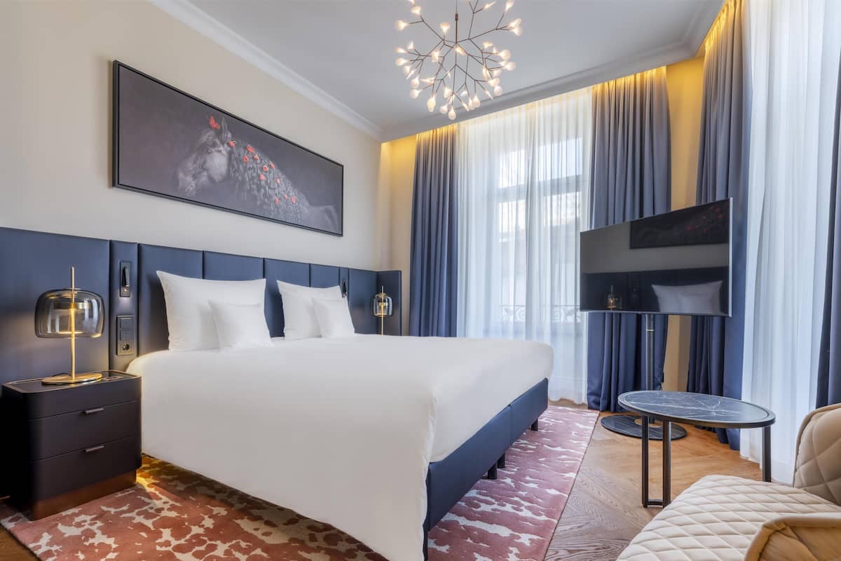 Une chambre d’hôtel moderne équipée d’un grand lit, d’un téléviseur à écran plat, d’un bureau et d’une chaise.