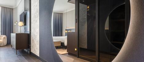 Une chambre d’hôtel moderne avec un mur incurvé, un lit, un coin salon et une grande fenêtre.