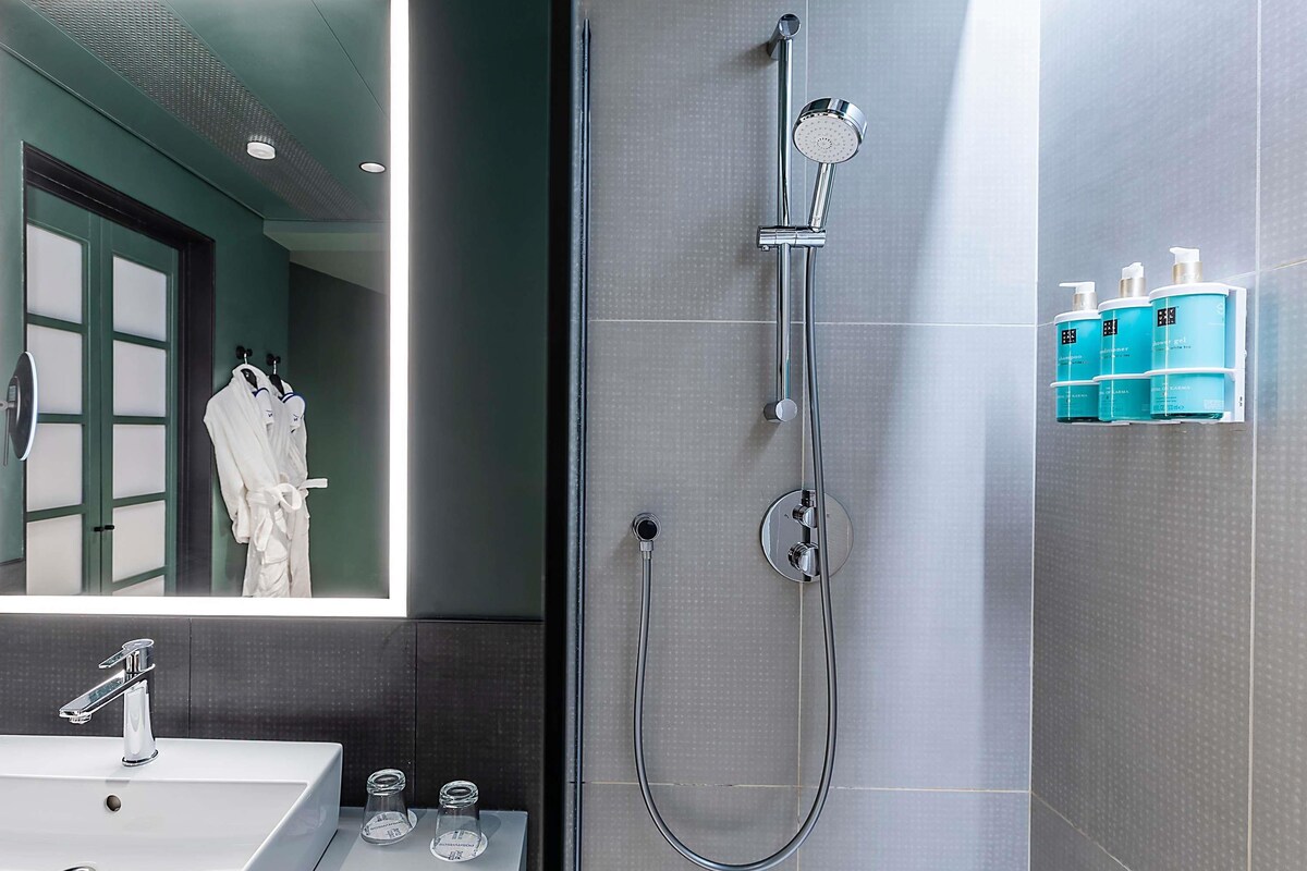 A modern bathroom with a large mirror, a shower, and a sink.