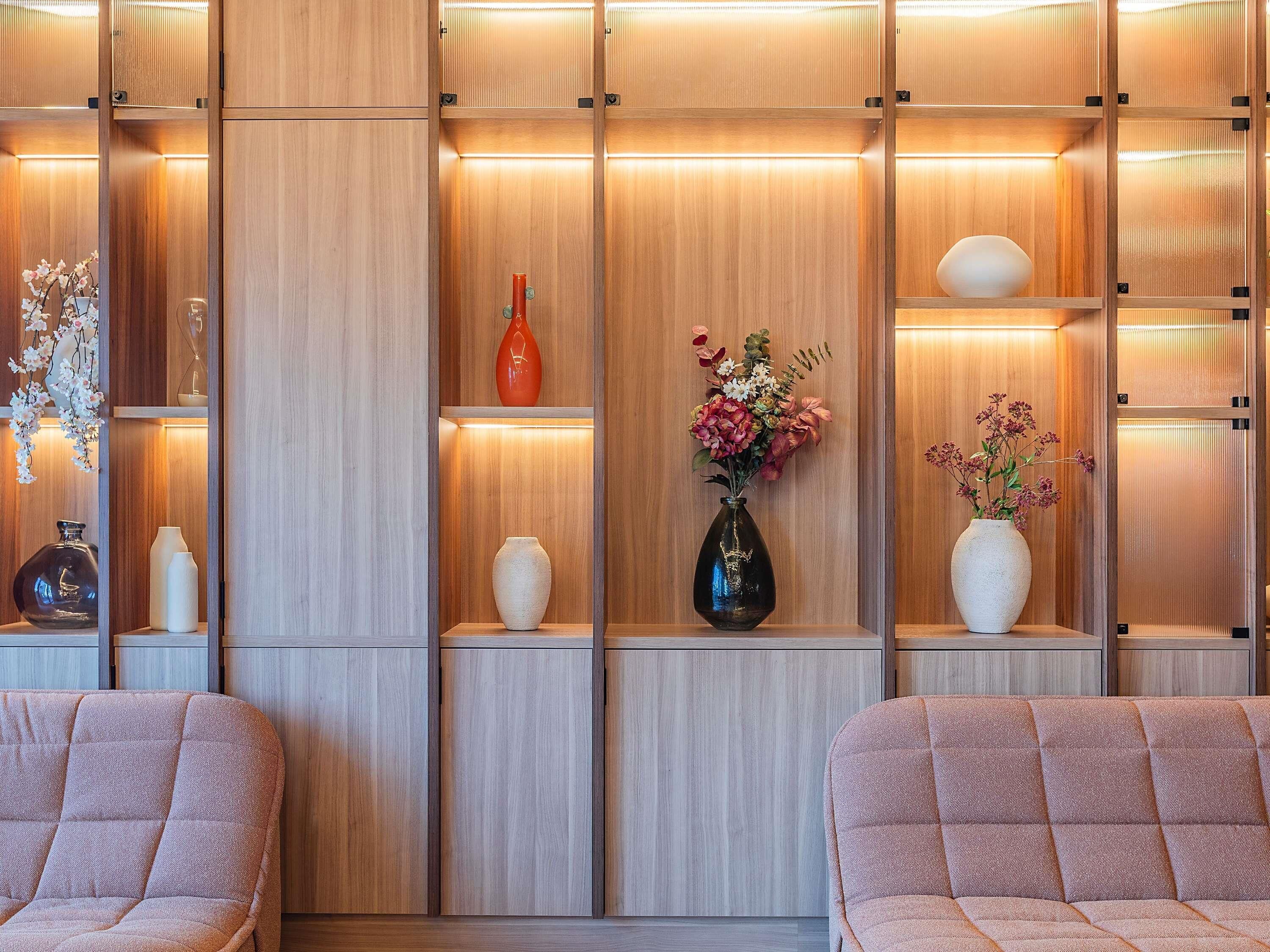 A modern interior with wooden paneling, shelves with decorative vases, and cushioned seating.