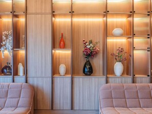 A modern interior with wooden paneling, shelves with decorative vases, and cushioned seating. - Novotel Lisboa (Lisbon)