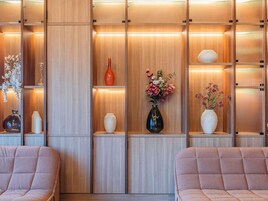 Un interior moderno con paneles de madera, estanterías con jarrones decorativos y asientos acolchados.