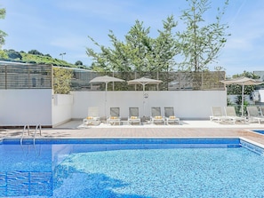Piscina a l'aire lliure de temporada, para-sols i gandules