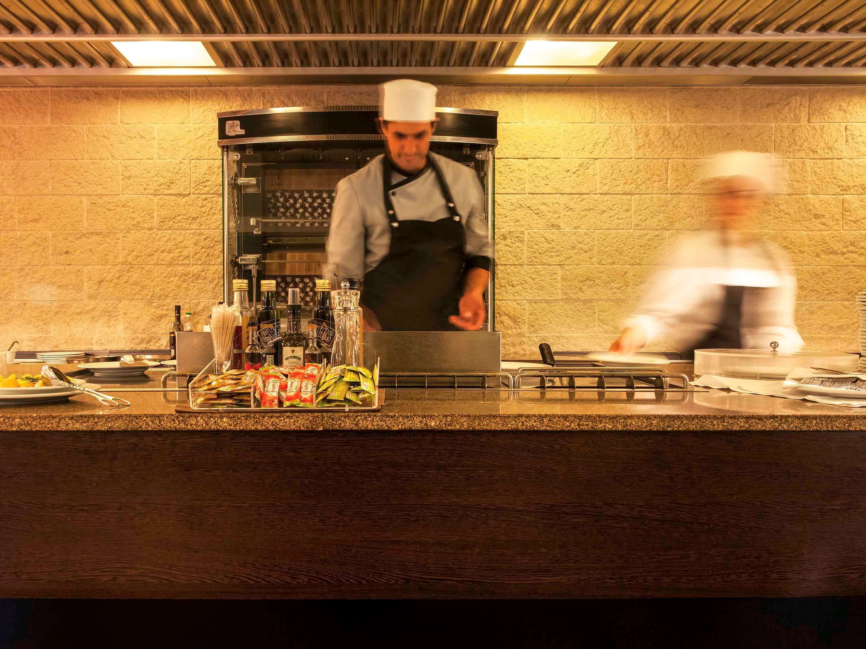 A chef in a kitchen with a brick wall and a modern oven.