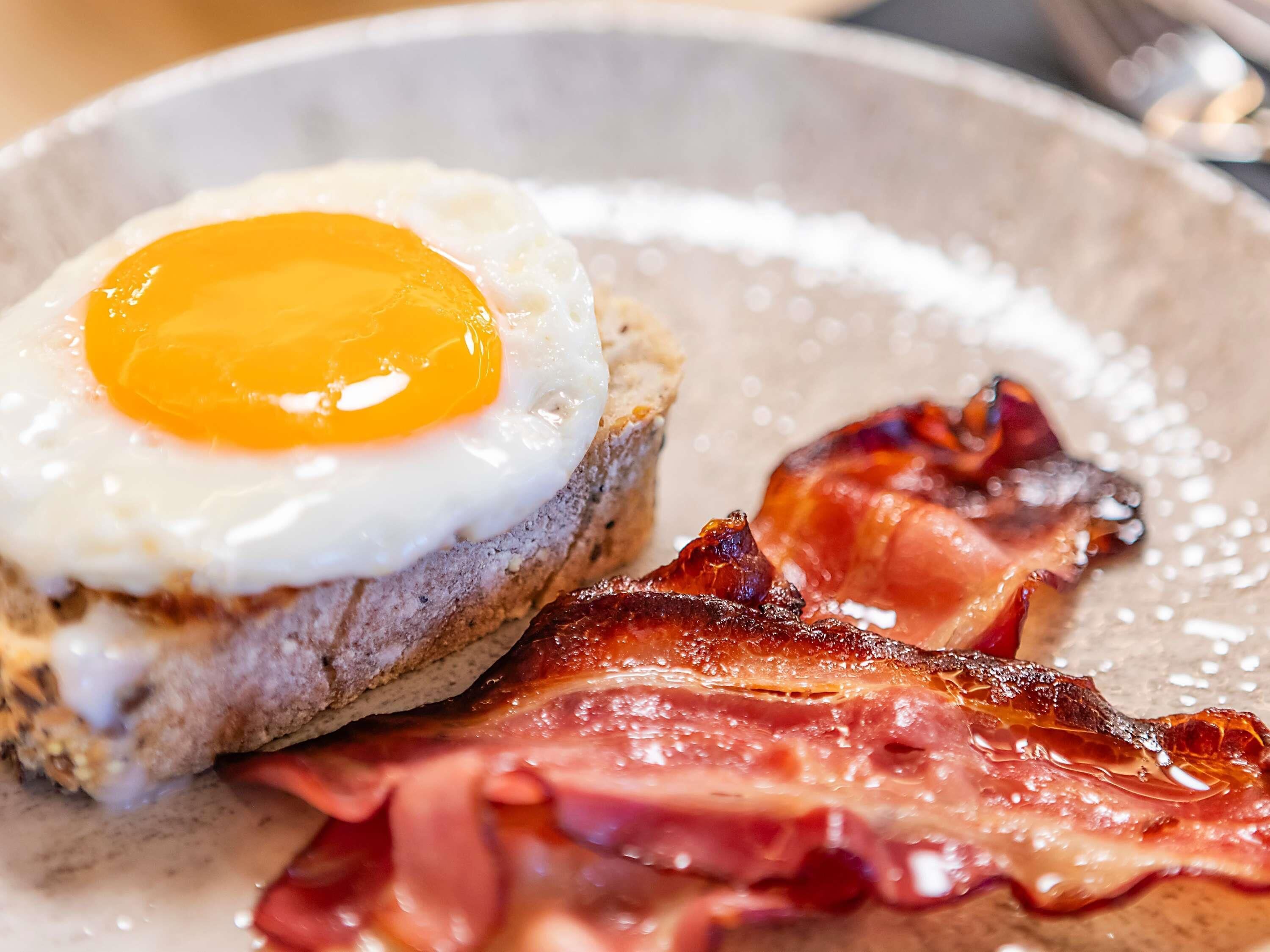 A breakfast plate with a fried egg, bacon, and toast.
