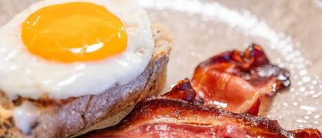 Un plato de desayuno con un huevo frito, tocino y tostadas.
