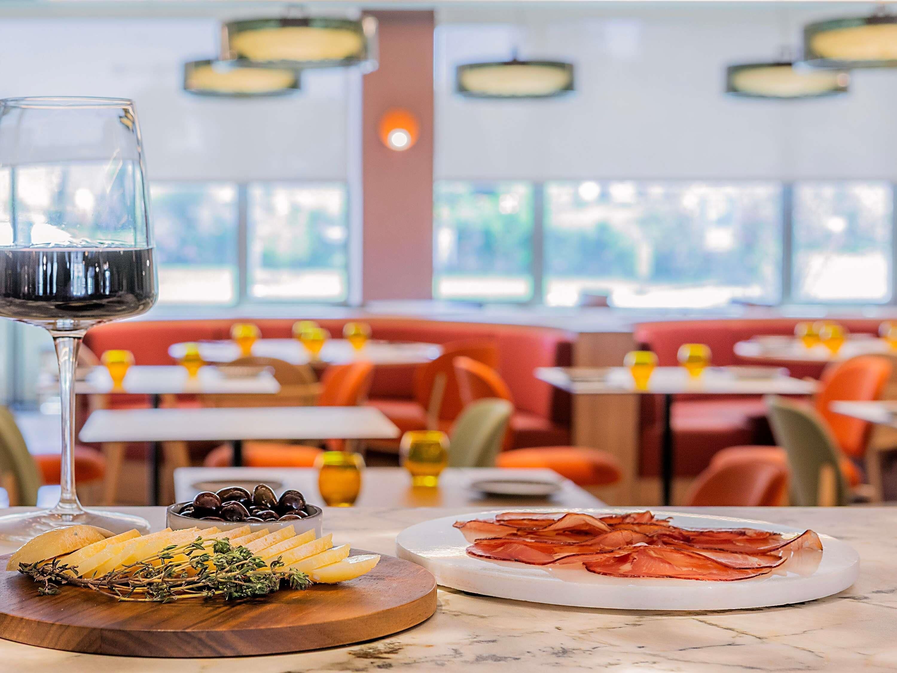 Un espace repas avec des tables, des chaises et un verre de vin rouge.