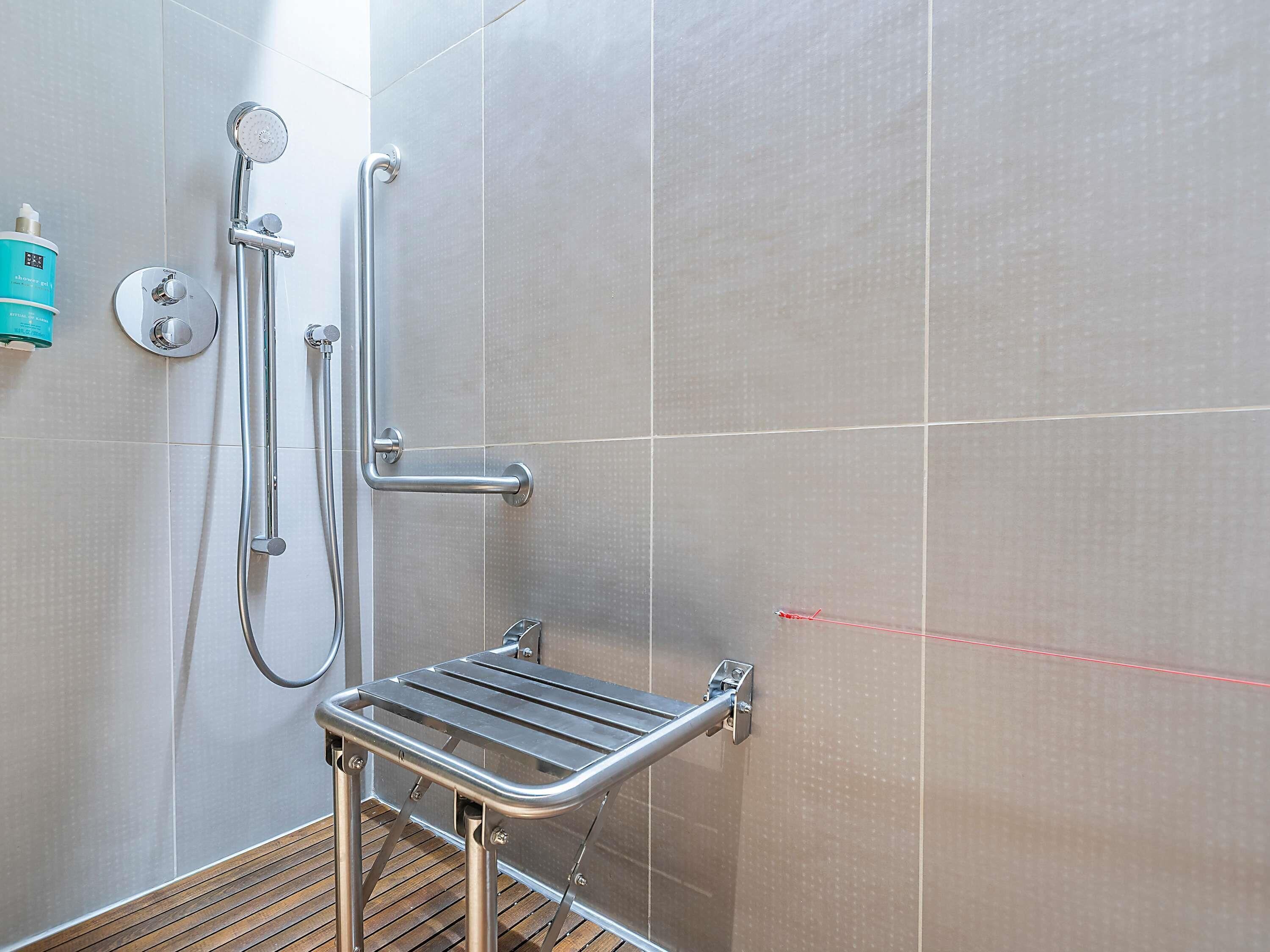 Un espace douche équipé d’une barre d’appui, d’un pommeau de douche à main et d’un flexible de douche à main.