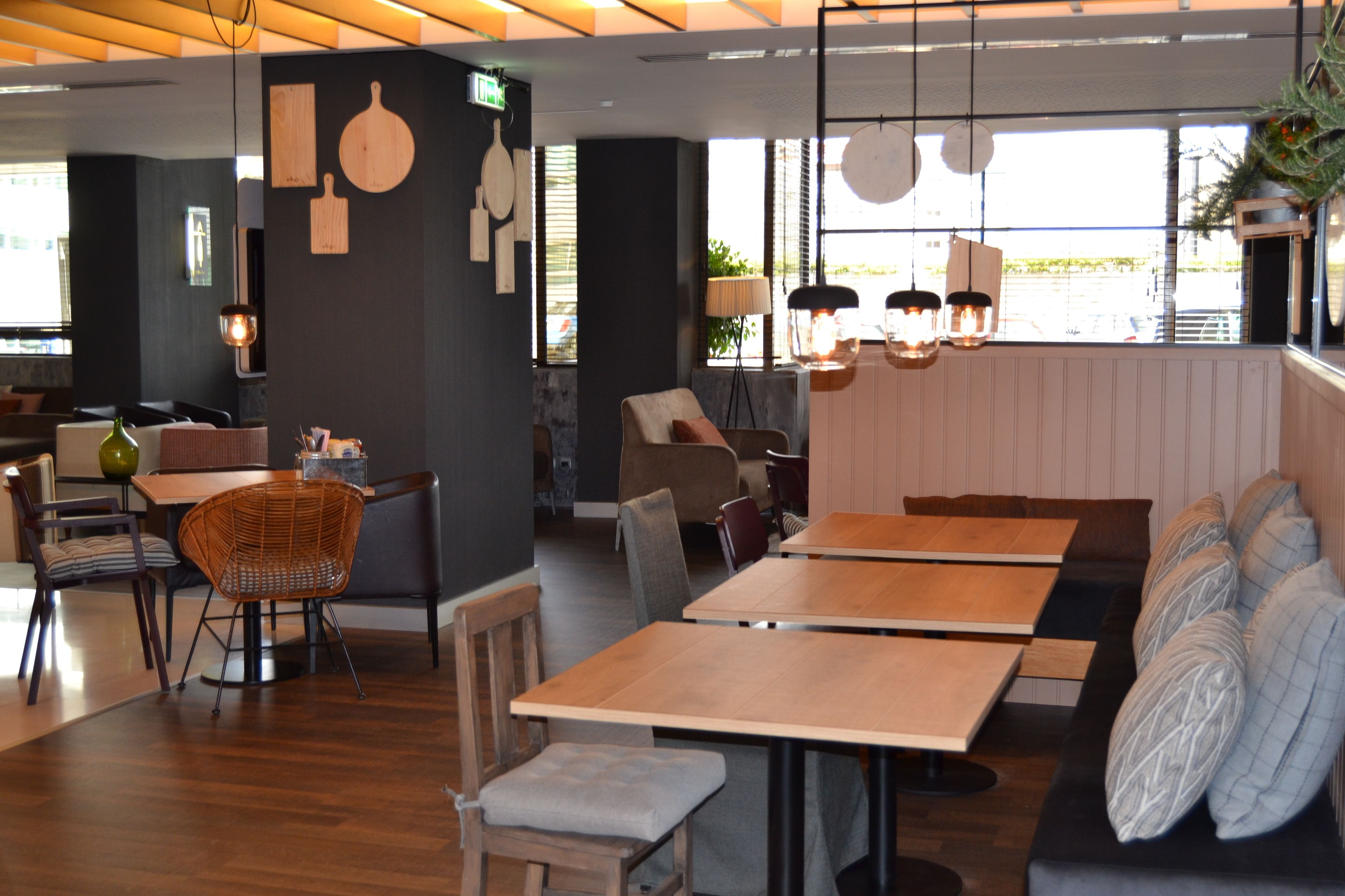 A restaurant interior with wooden tables and chairs, a bar area, and a seating section with cushioned benches.
