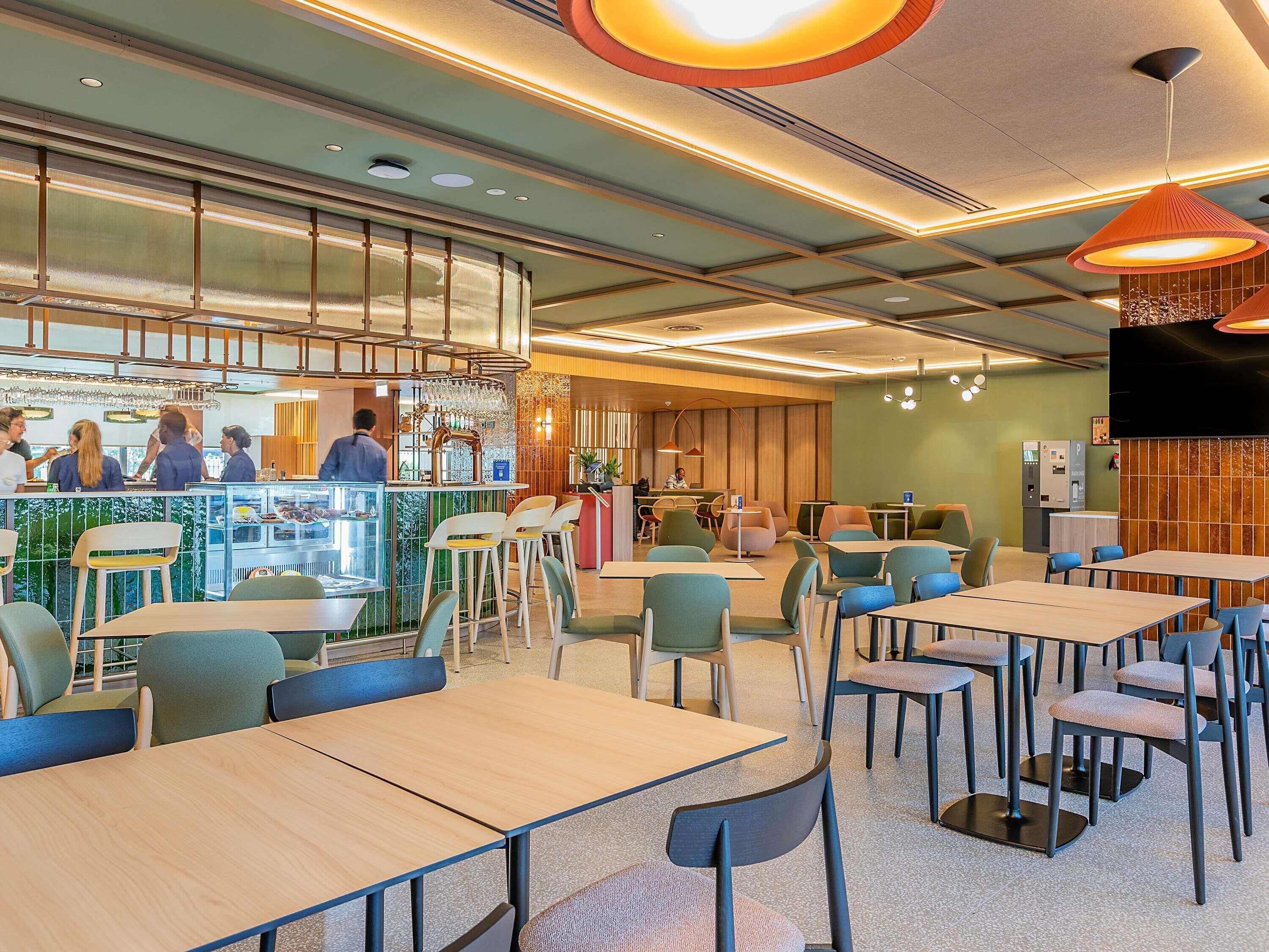 Un interior de restaurante moderno con asientos de bar, mesas y una barra.
