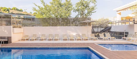 A swimming pool with lounge chairs and a wooden deck.