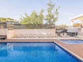 Una piscina con sillas de descanso y una terraza de madera.
