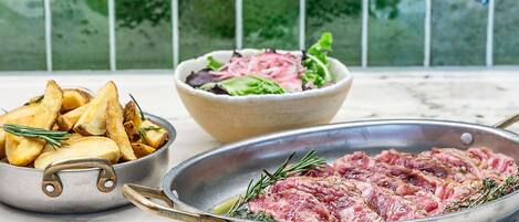 A meal with roasted meat, potatoes, and a salad on a table.