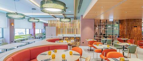 A modern restaurant interior with round tables, orange seating, and pendant lighting.