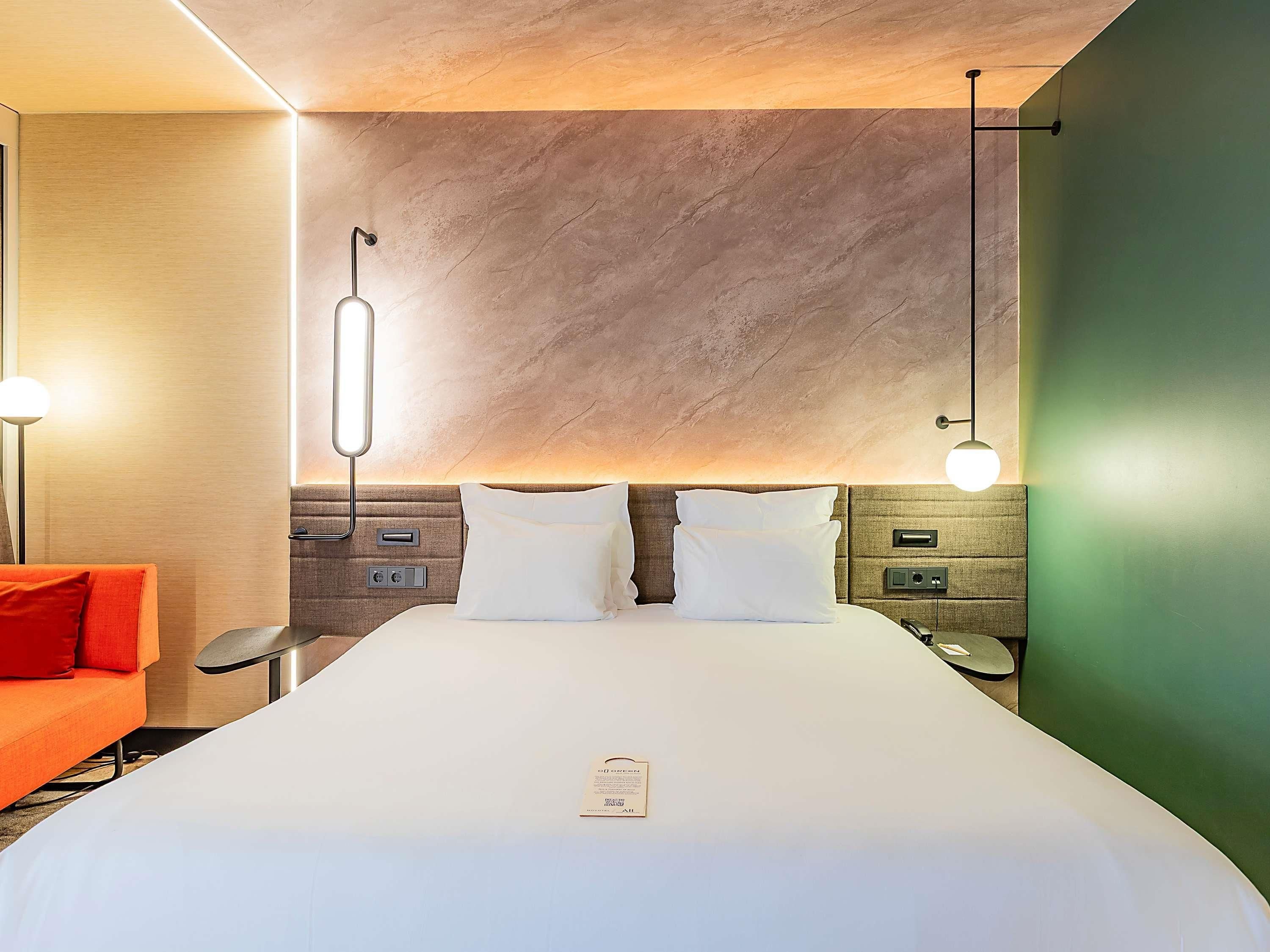 Une chambre d’hôtel avec un grand lit, une table de chevet, un bureau et un canapé rouge.