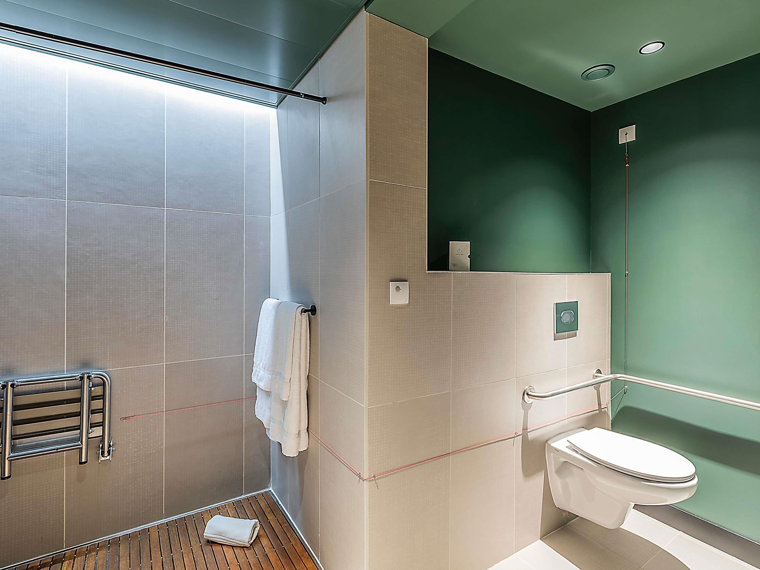 Et moderne badeværelse med bruser, toilet og håndklædestang.