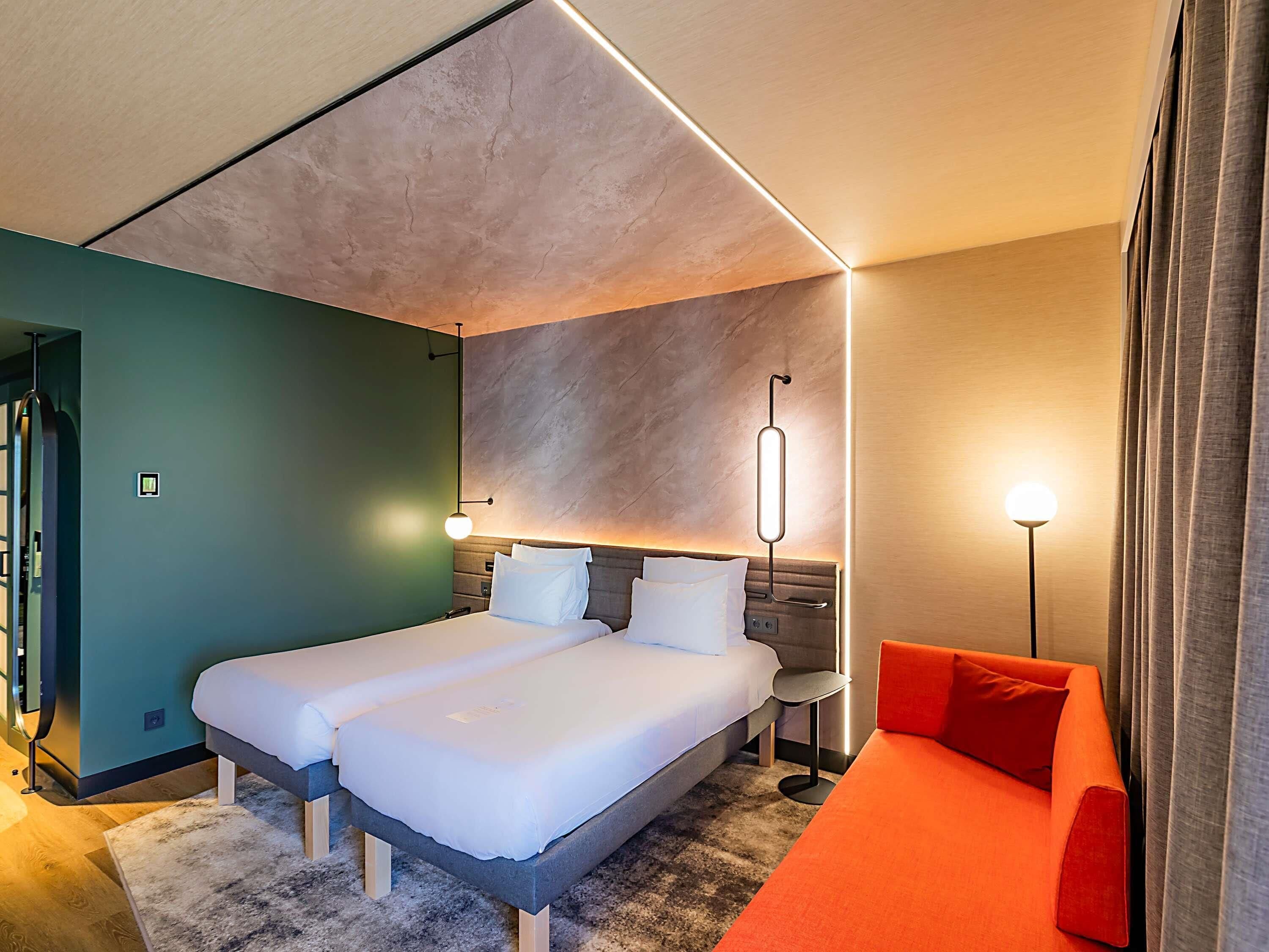 Une chambre d’hôtel moderne avec un grand lit, un bureau et un canapé rouge.