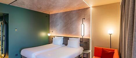 Een moderne hotelkamer met een groot bed, een bureau en een rode bank.