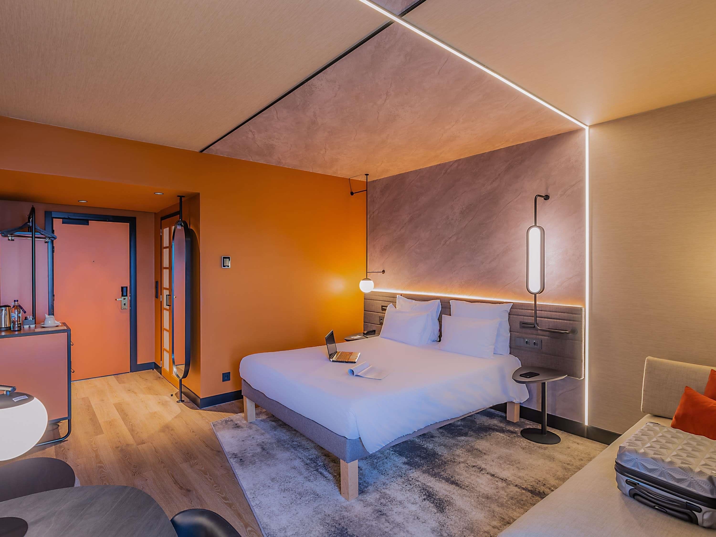A modern hotel room with a large bed, bedside tables, a desk, and a chair.