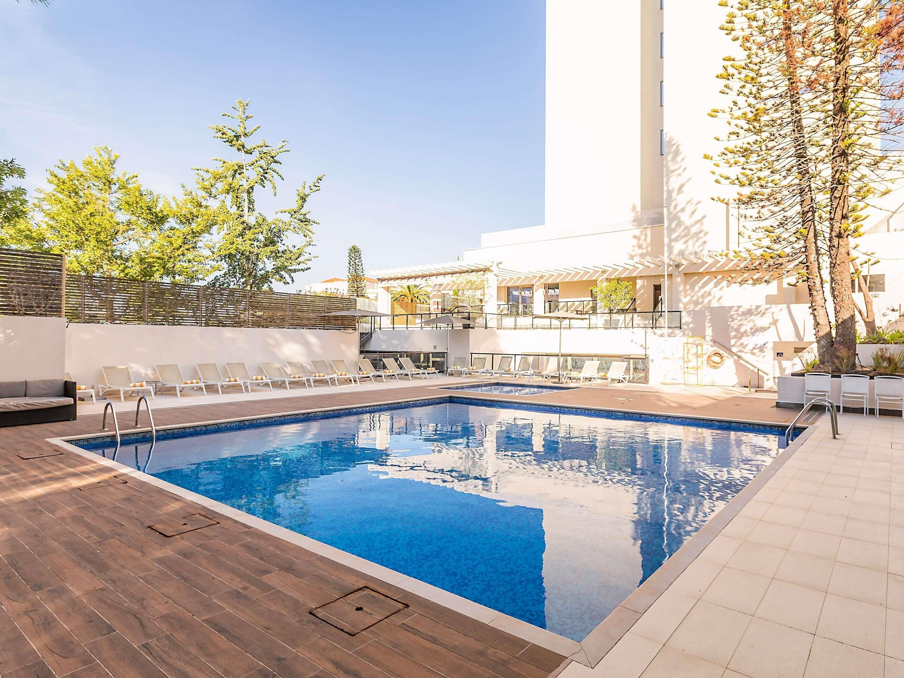 Une piscine avec des chaises longues et une terrasse en bois.