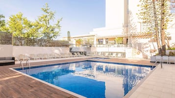 Ein Schwimmbecken mit Liegestühlen und einer Holzterrasse.