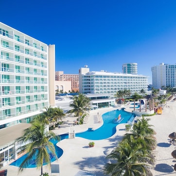 A resort with a large pool, palm trees, and a beach.