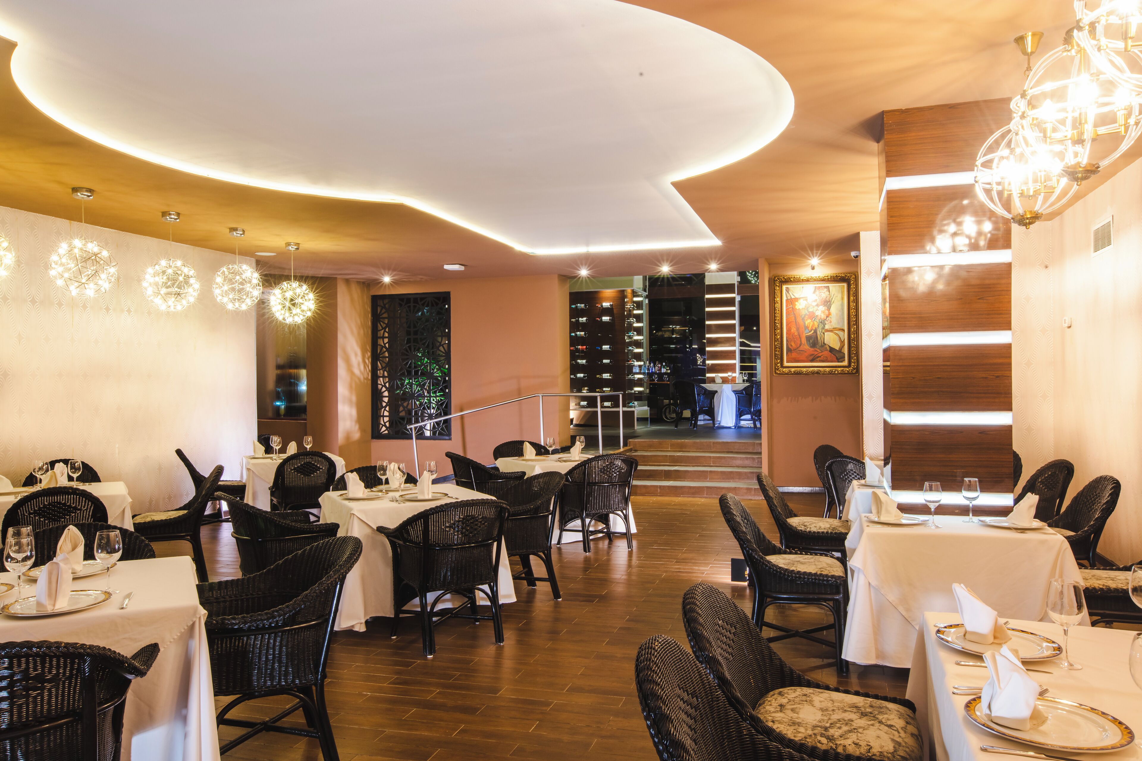 Un restaurante con mesas redondas, sillas de mimbre negro y techo de madera.
