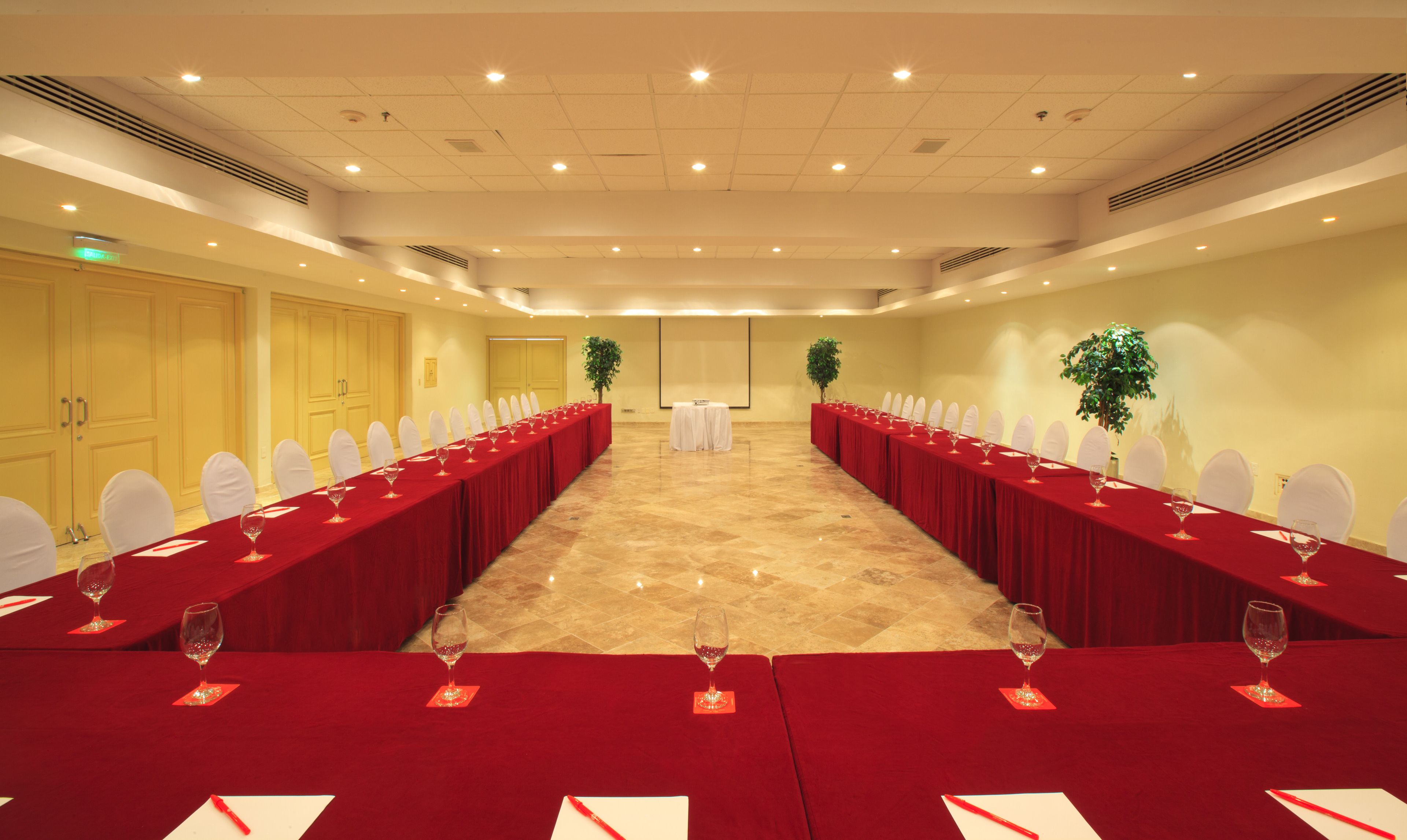 A conference room with a long table set for a meeting, equipped with chairs and wine glasses.
