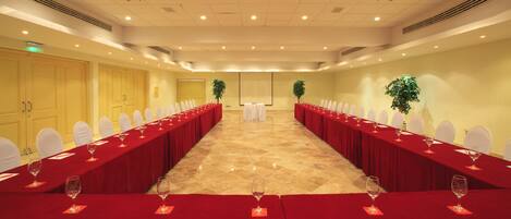 A conference room with a long table set for a meeting, equipped with chairs and wine glasses.