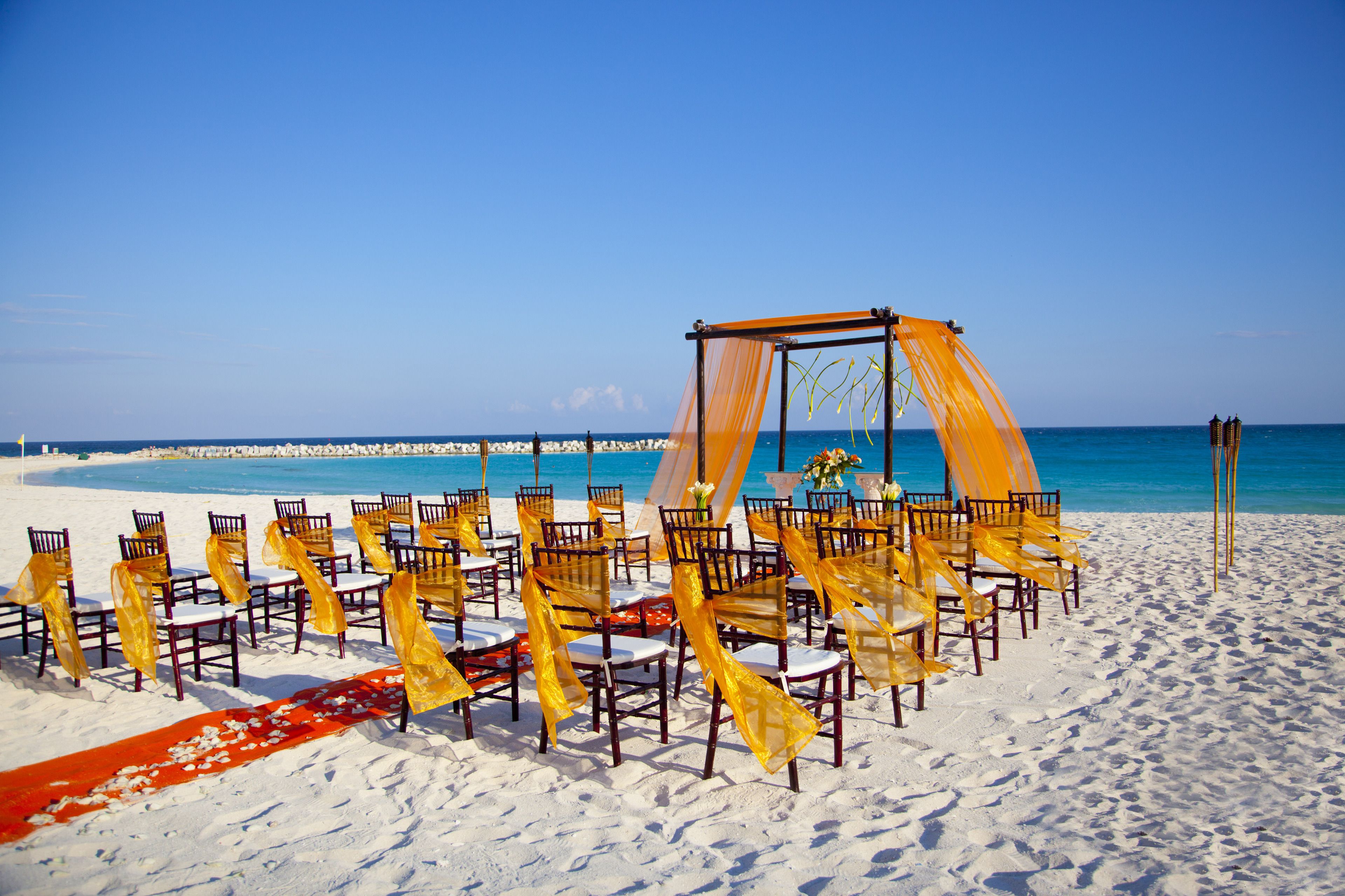 A beach ceremony setup with chairs and a canopy.