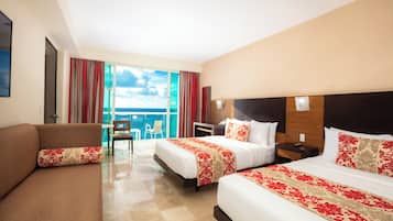 A hotel room with two beds, a sofa, a chair, and a view of the ocean.