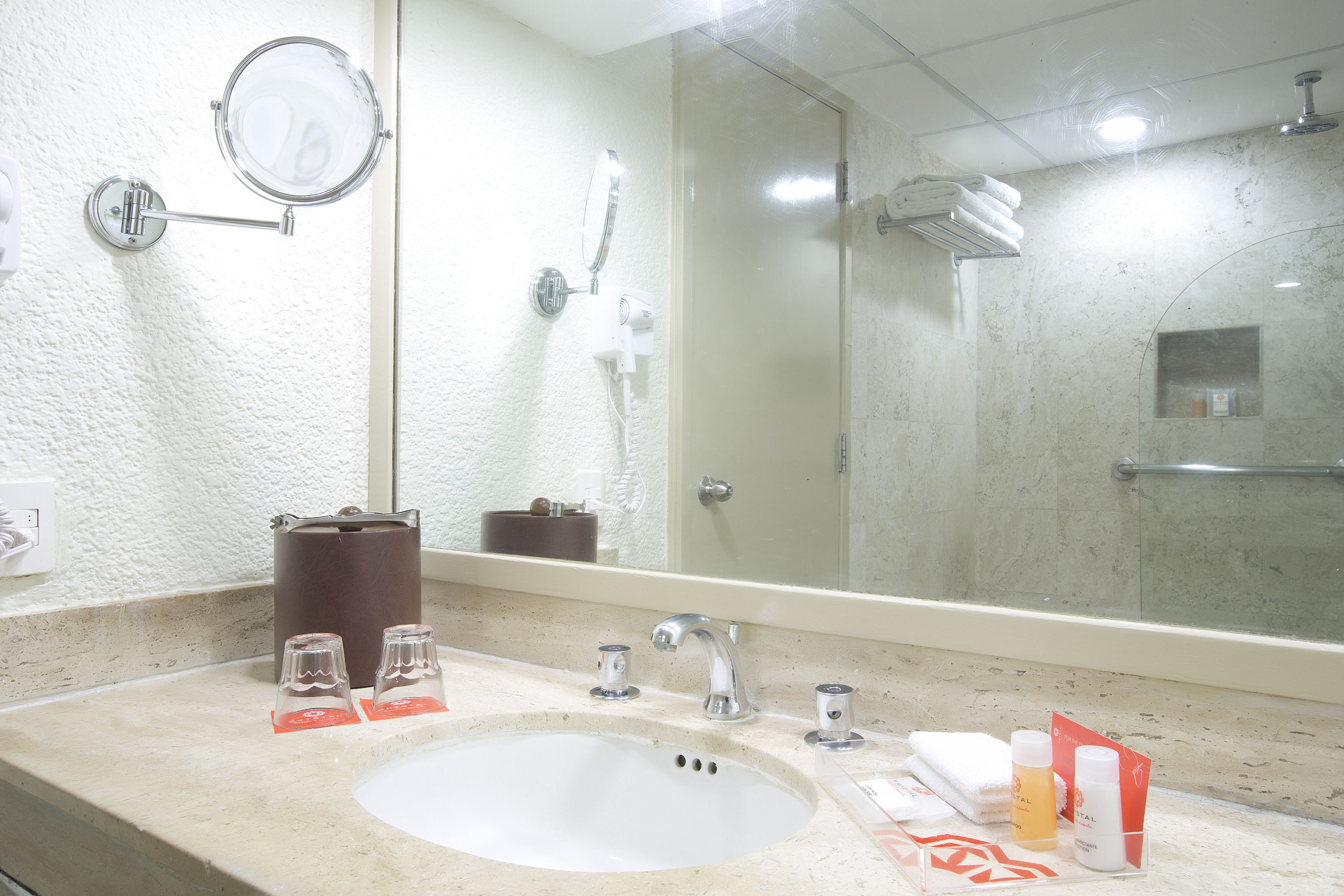 A bathroom with a sink, mirror, and shower.