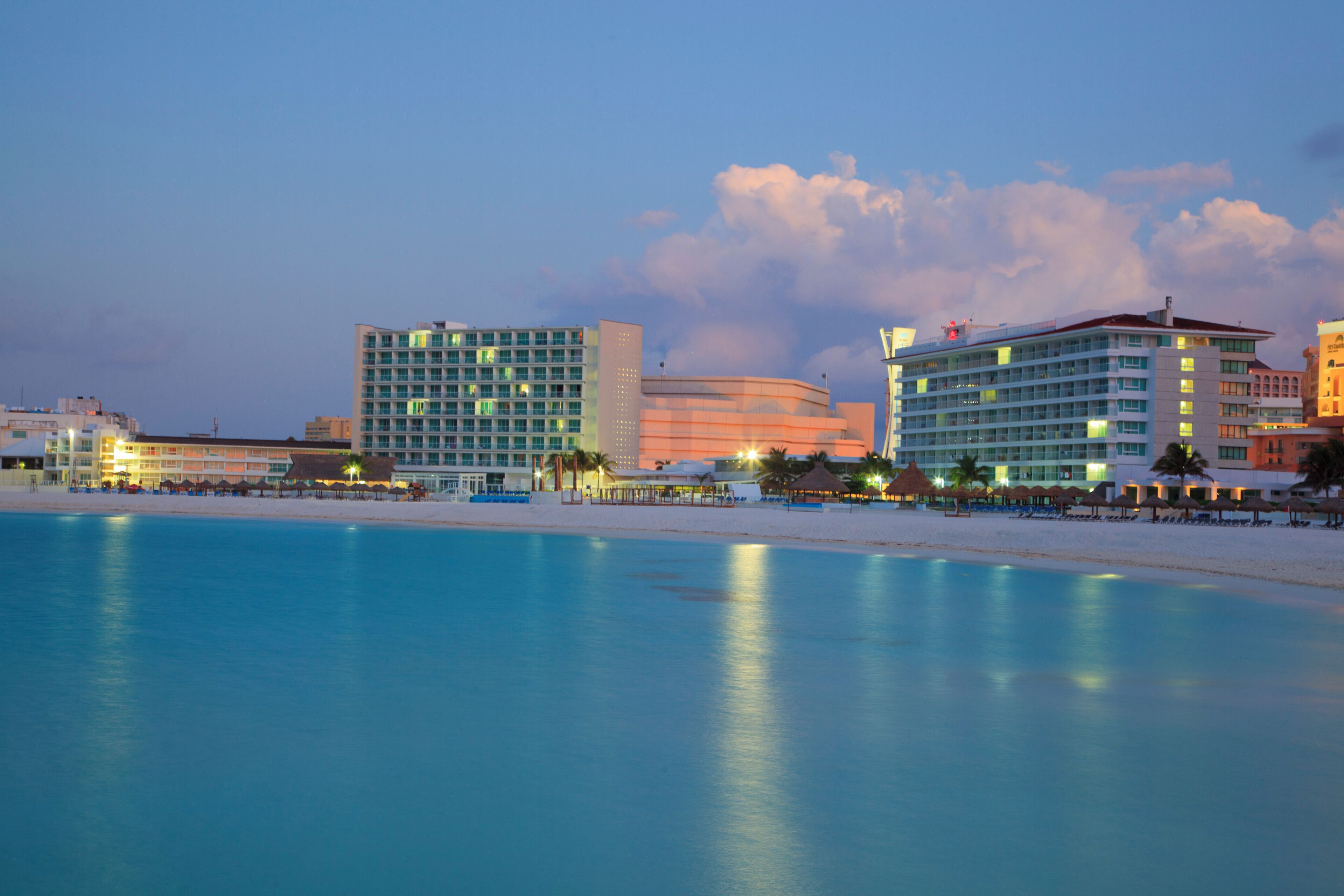 A beachfront hotel with multiple buildings, a sandy beach, and a calm sea.