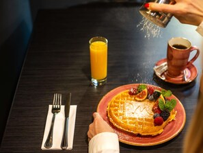 Een ontbijtsetting met een bord eten, een glas sinaasappelsap en een kop koffie op een tafel.