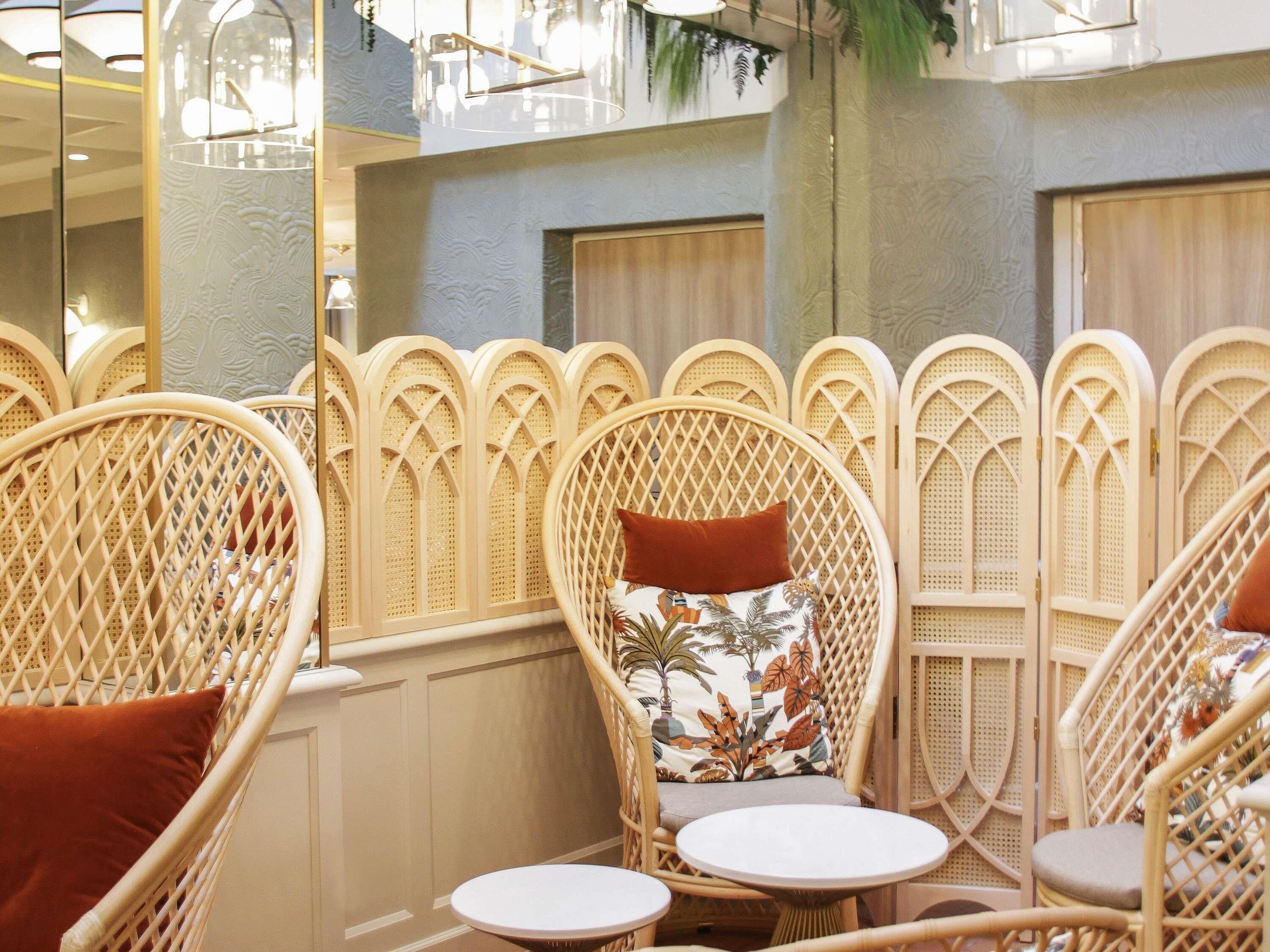 Wicker chairs with cushions, a small round table, and a decorative wall with a geometric pattern.